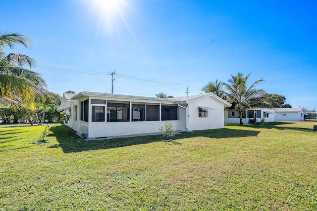 back of property with a lawn and a sunroom