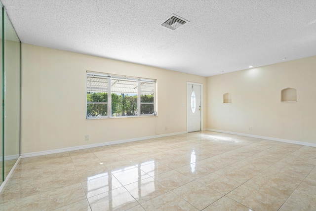 spare room with light tile patterned floors and a textured ceiling