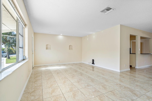 spare room featuring light tile patterned floors and a textured ceiling