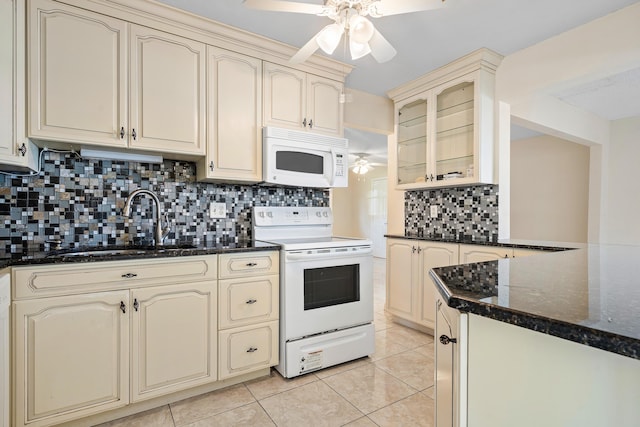 kitchen featuring white appliances, cream cabinets, sink, decorative backsplash, and dark stone countertops