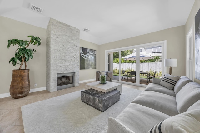 living room with light tile patterned floors, baseboards, a fireplace, and visible vents