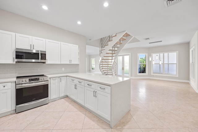 kitchen featuring white cabinets, decorative backsplash, light tile patterned floors, kitchen peninsula, and stainless steel appliances