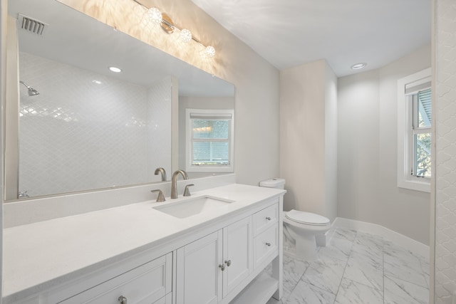 bathroom with vanity, toilet, and tiled shower