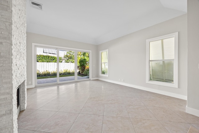 tiled empty room featuring a stone fireplace