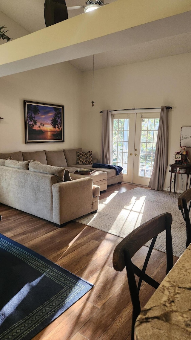 living room with hardwood / wood-style floors, high vaulted ceiling, and french doors