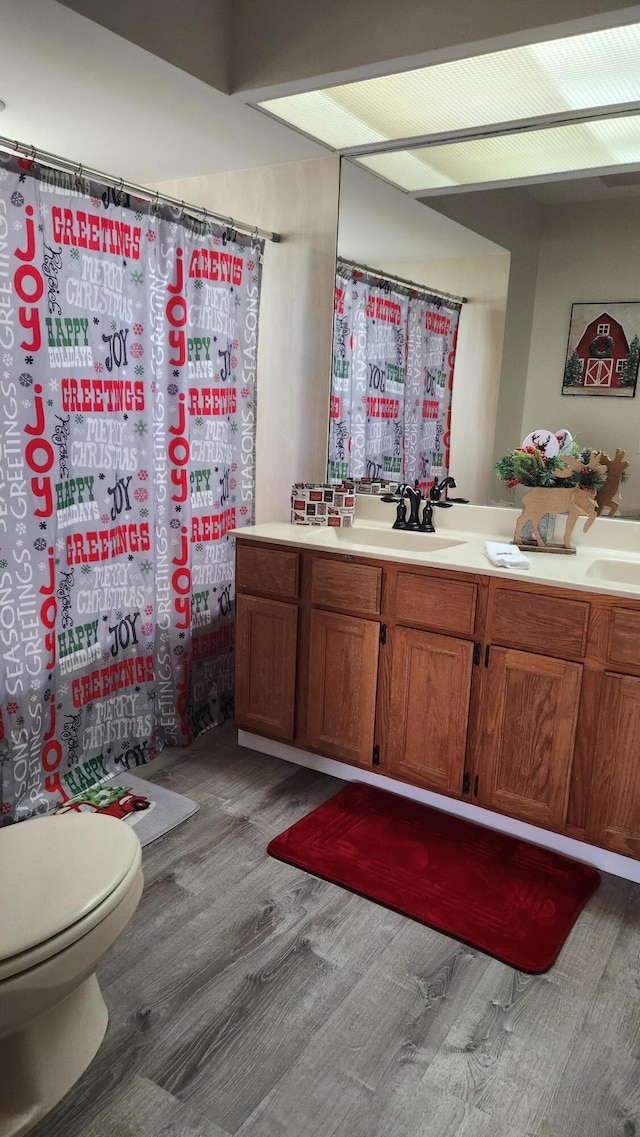 bathroom with vanity, wood-type flooring, toilet, and walk in shower