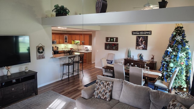 living room with ceiling fan, dark hardwood / wood-style flooring, a towering ceiling, and sink