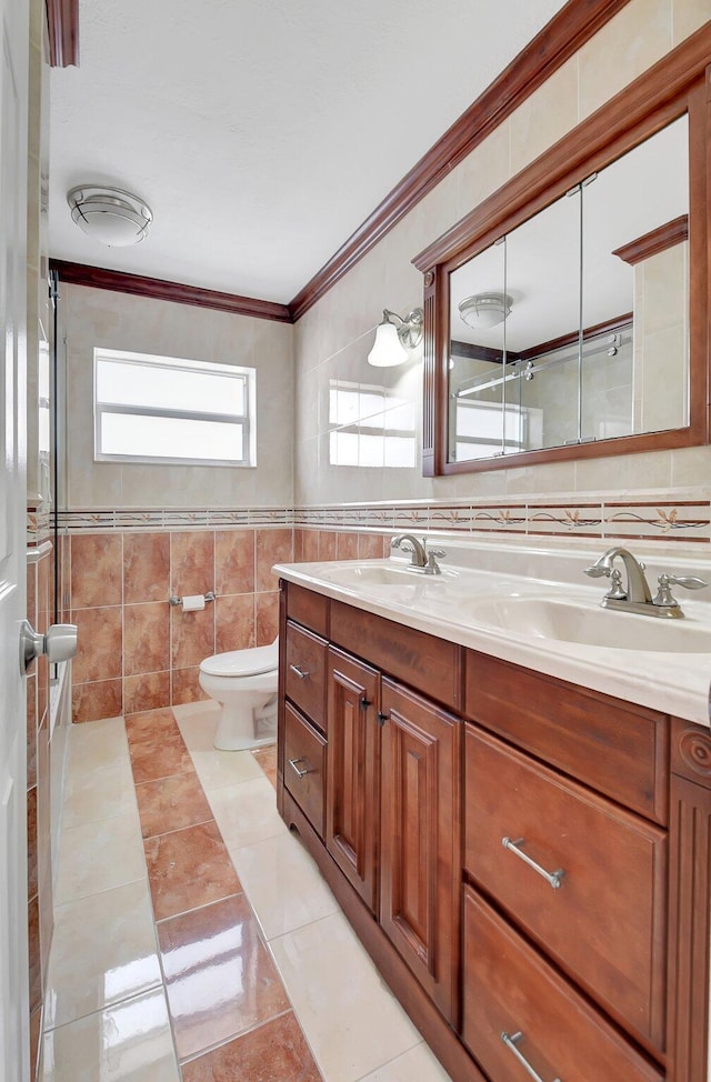 bathroom featuring vanity, tile patterned floors, crown molding, toilet, and tile walls