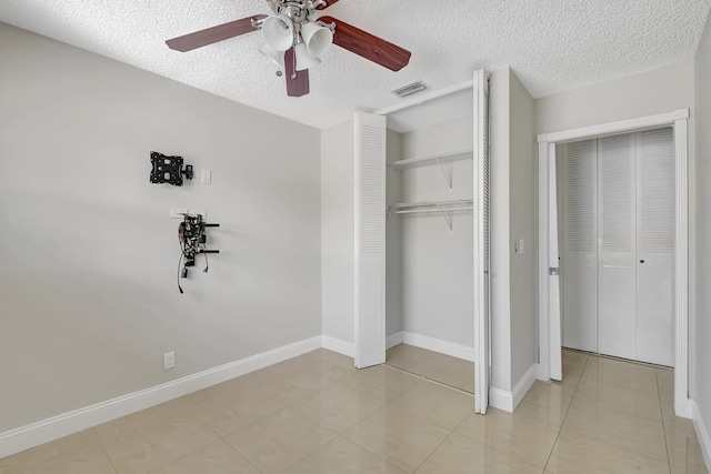 unfurnished bedroom with ceiling fan, light tile patterned floors, and a textured ceiling