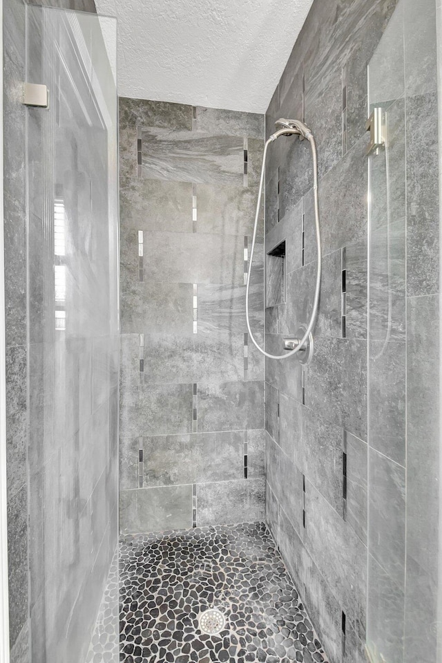 bathroom with tiled shower and a textured ceiling