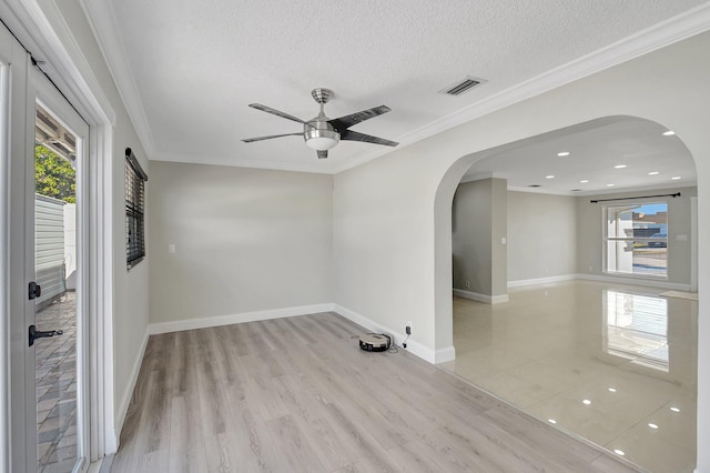 spare room featuring ceiling fan, crown molding, light wood-type flooring, and a textured ceiling