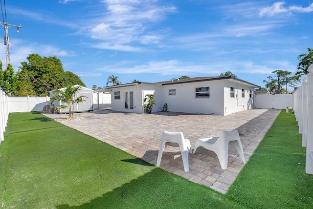 back of property with a shed, a yard, and a patio