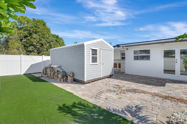 back of property with a patio, a storage shed, and a lawn