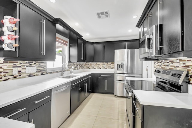 kitchen with appliances with stainless steel finishes, tasteful backsplash, ornamental molding, sink, and light tile patterned flooring