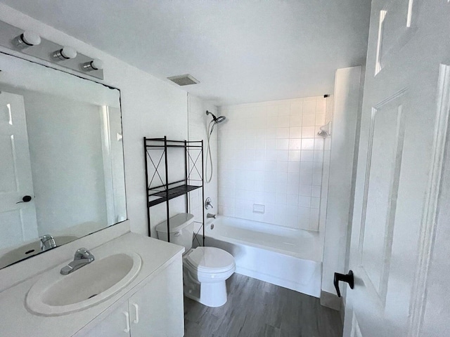 full bathroom with vanity, tiled shower / bath combo, hardwood / wood-style flooring, and toilet