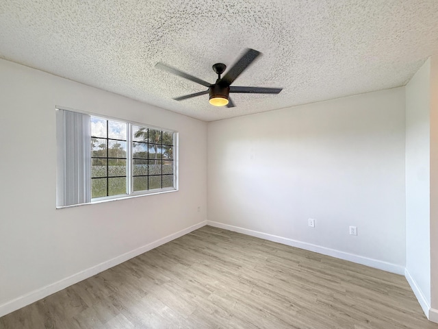 unfurnished room featuring ceiling fan, a textured ceiling, light wood-style flooring, and baseboards