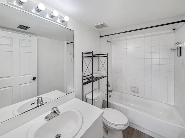 bathroom with visible vents, toilet, wood finished floors, vanity, and shower / bathing tub combination