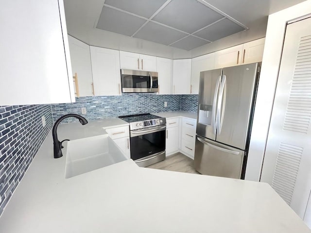 kitchen with white cabinets, sink, light hardwood / wood-style flooring, appliances with stainless steel finishes, and tasteful backsplash