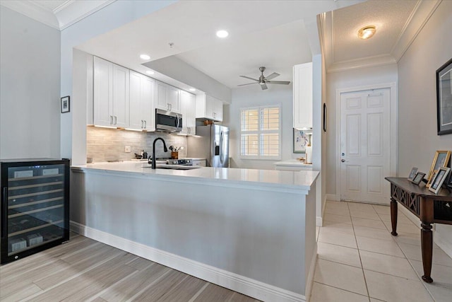 kitchen featuring kitchen peninsula, appliances with stainless steel finishes, white cabinets, and wine cooler