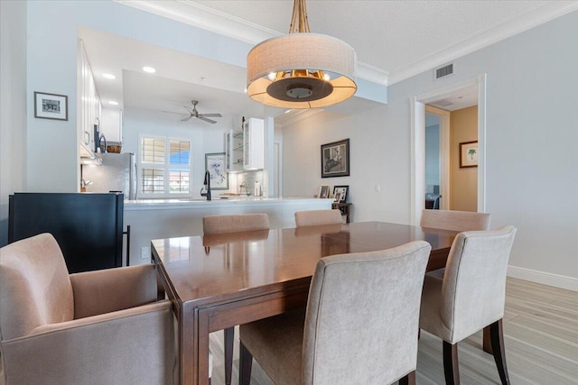 dining room featuring light hardwood / wood-style floors, ceiling fan, ornamental molding, and sink