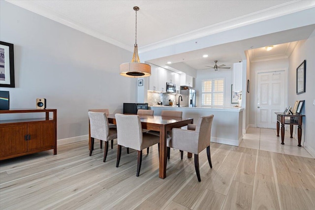 dining area with ceiling fan, sink, light wood-type flooring, and crown molding