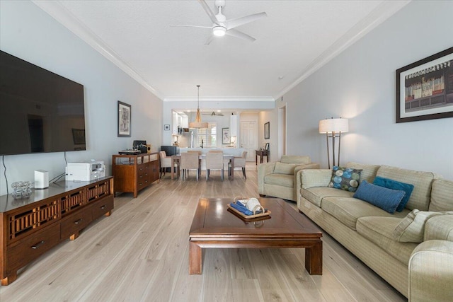 living room featuring crown molding, ceiling fan, and light hardwood / wood-style floors