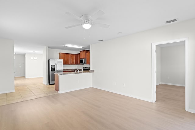 kitchen featuring kitchen peninsula, light wood-type flooring, ceiling fan with notable chandelier, and appliances with stainless steel finishes