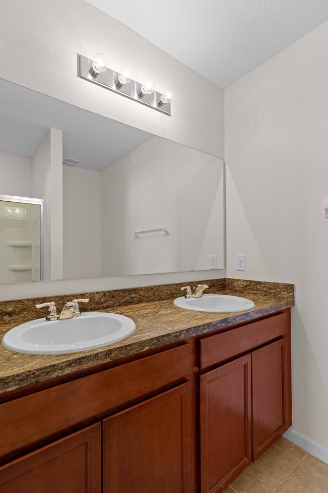 bathroom featuring tile patterned flooring, vanity, a shower with shower door, and a textured ceiling