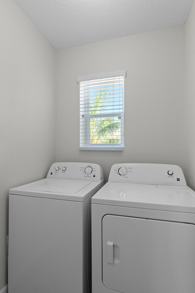 clothes washing area with washer and dryer and a textured ceiling