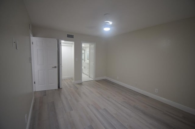 unfurnished bedroom with connected bathroom and light wood-type flooring