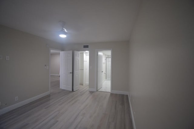 unfurnished bedroom with light wood-type flooring, ensuite bathroom, and ceiling fan