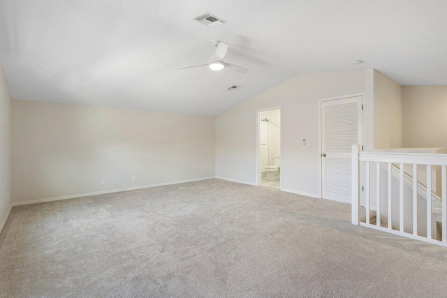 spare room featuring ceiling fan, light carpet, and vaulted ceiling