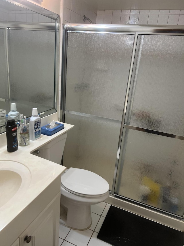 bathroom with tile patterned flooring, vanity, a shower with door, and toilet