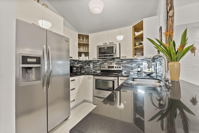 kitchen with sink, lofted ceiling, decorative backsplash, white cabinets, and appliances with stainless steel finishes