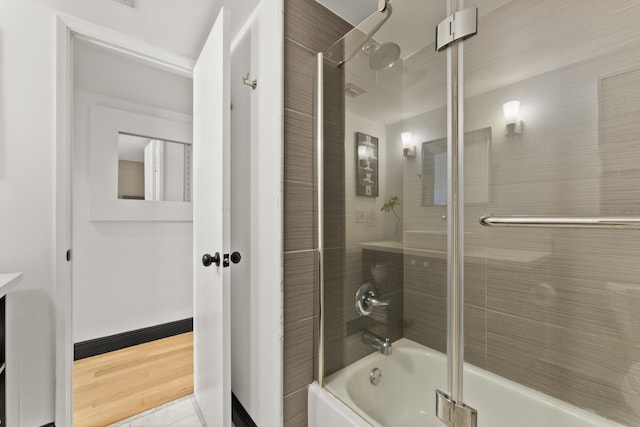 bathroom featuring wood-type flooring and shower / bath combination with glass door