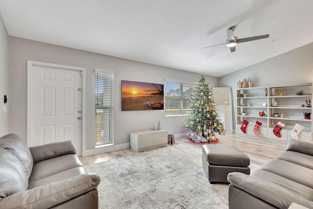 living room with light hardwood / wood-style floors, vaulted ceiling, and ceiling fan