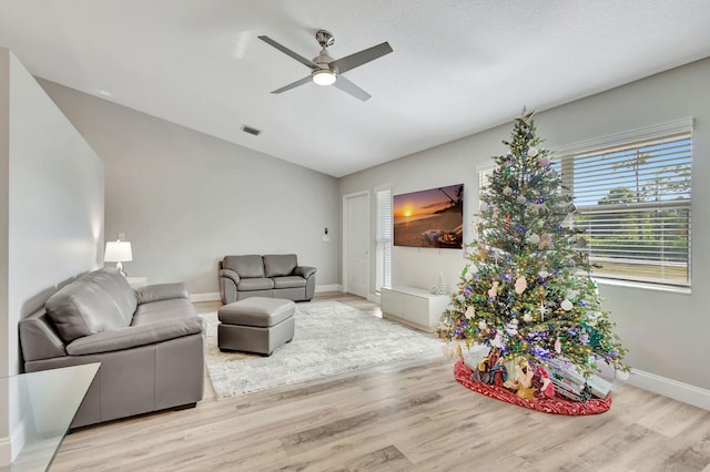 living room with ceiling fan, lofted ceiling, and light wood-type flooring