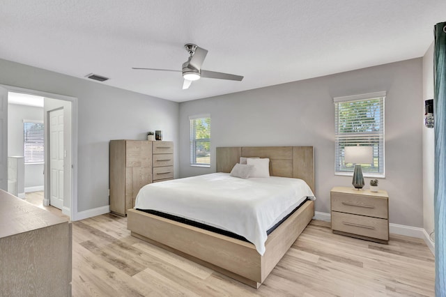 bedroom featuring multiple windows, ceiling fan, a textured ceiling, and light wood-type flooring