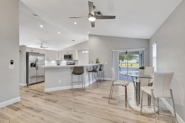 kitchen featuring white cabinetry, kitchen peninsula, lofted ceiling, appliances with stainless steel finishes, and light wood-type flooring