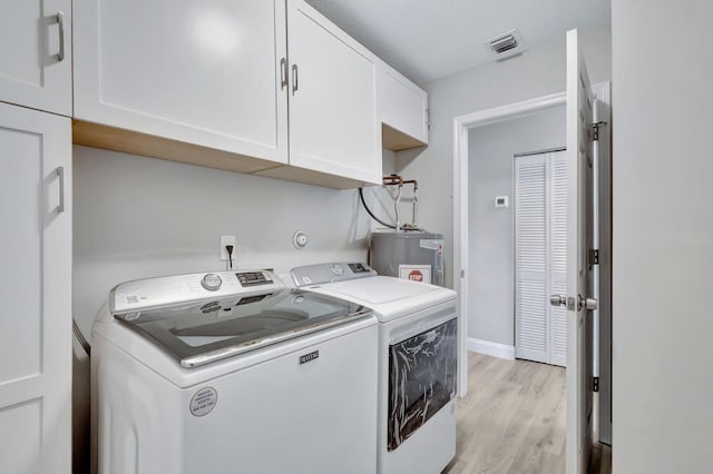 laundry room with washer and clothes dryer, electric water heater, light hardwood / wood-style flooring, and cabinets