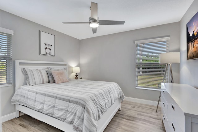 bedroom with ceiling fan, light wood-type flooring, and multiple windows