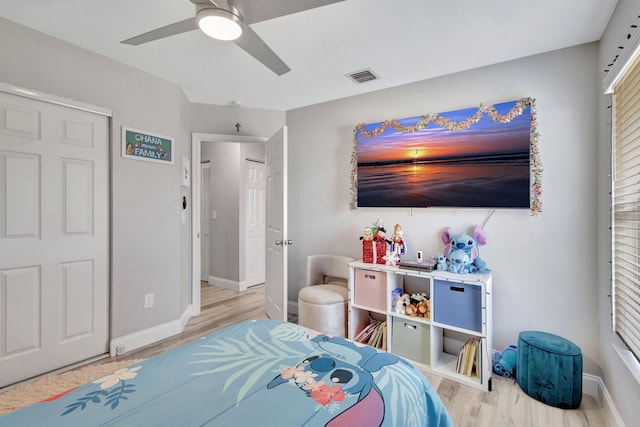 bedroom featuring ceiling fan, a closet, multiple windows, and light hardwood / wood-style flooring