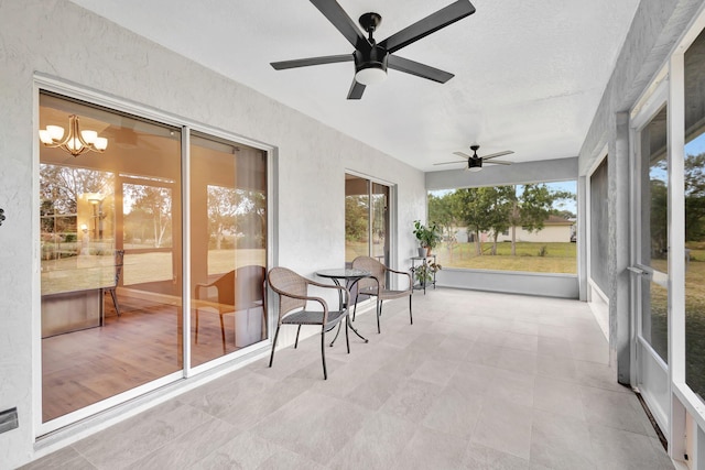 sunroom / solarium with ceiling fan with notable chandelier