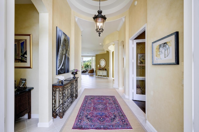 hall featuring crown molding, a chandelier, and light tile patterned floors