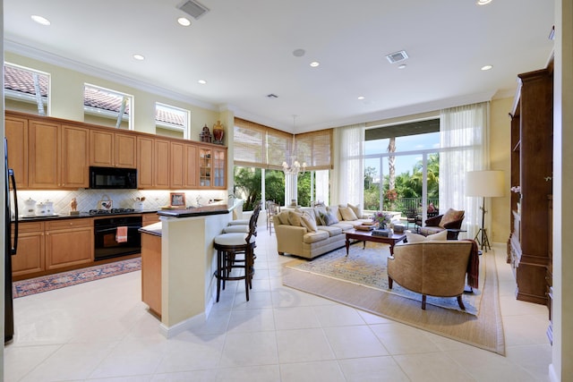 kitchen with ornamental molding, light tile patterned floors, a kitchen breakfast bar, and black appliances