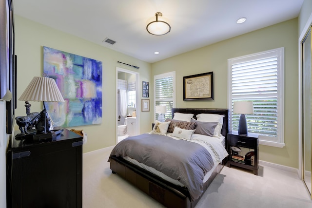 bedroom featuring light carpet and ensuite bath