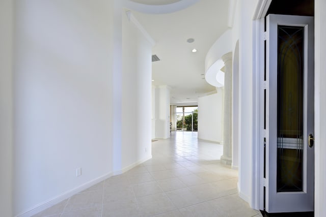 hallway featuring decorative columns, ornamental molding, and light tile patterned floors