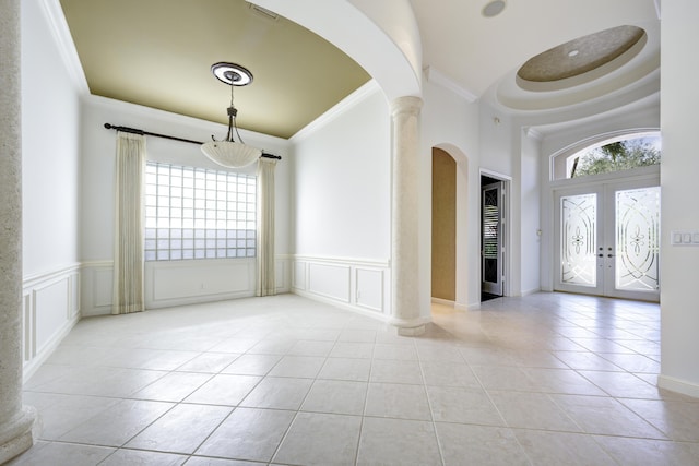 interior space with french doors, ornamental molding, a tray ceiling, plenty of natural light, and decorative columns