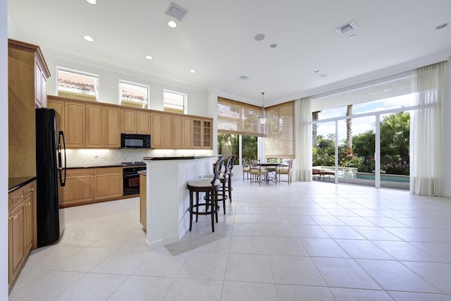 kitchen with hanging light fixtures, plenty of natural light, light tile patterned floors, and black appliances