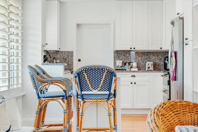 kitchen with white cabinets, dark stone counters, and light wood-type flooring